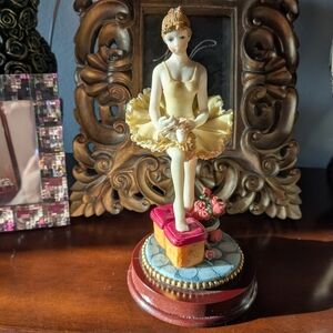 Elegant Ballerina Figurine With Yellow Dress Standing On A Wooden Stand.